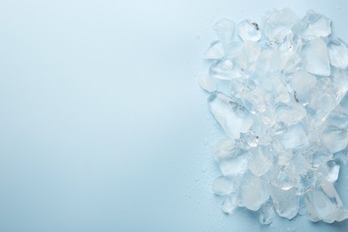 Photo of Pieces of crushed ice on light blue background, top view. Space for text