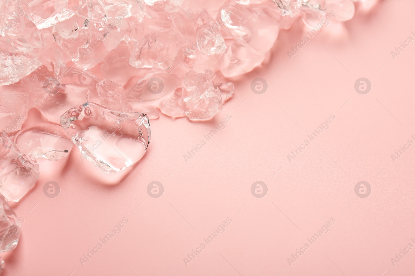 Photo of Pieces of crushed ice on pink background, top view. Space for text