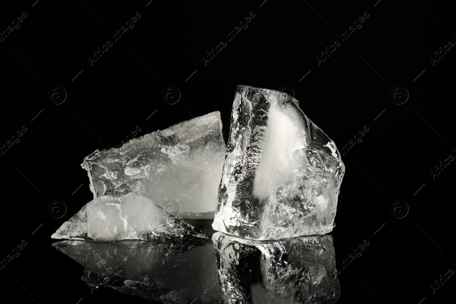 Photo of Pieces of clear ice on black mirror surface