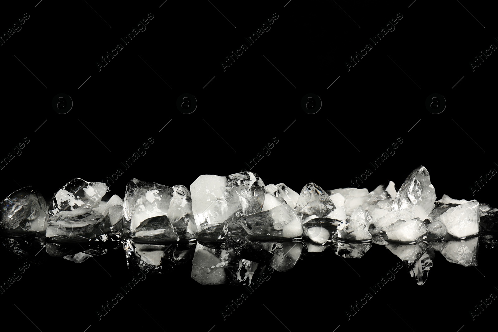 Photo of Pile of crushed ice on black mirror surface