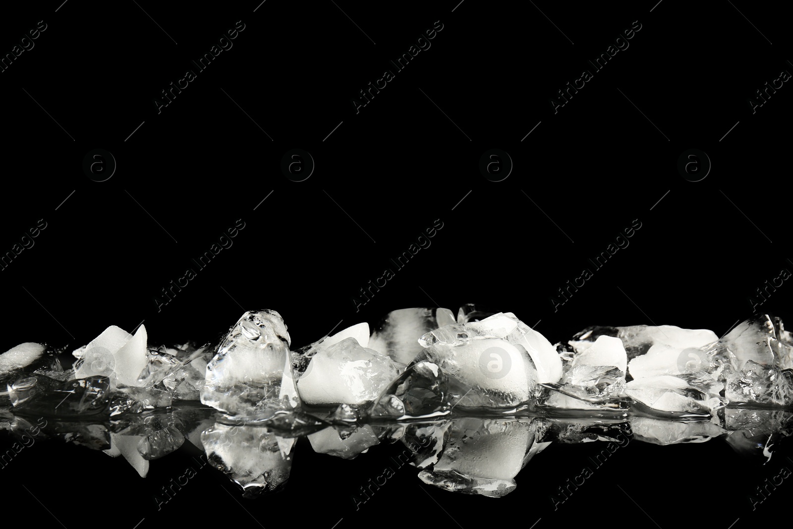 Photo of Pile of crushed ice on black mirror surface, space for text