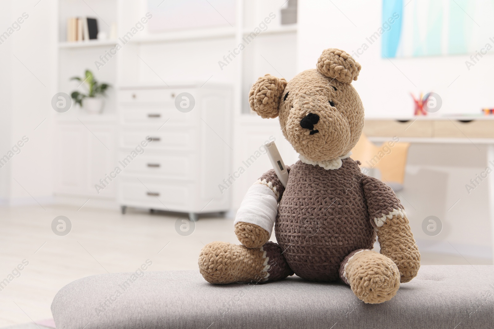 Photo of Toy cute bear with bandage and thermometer indoors, space for text