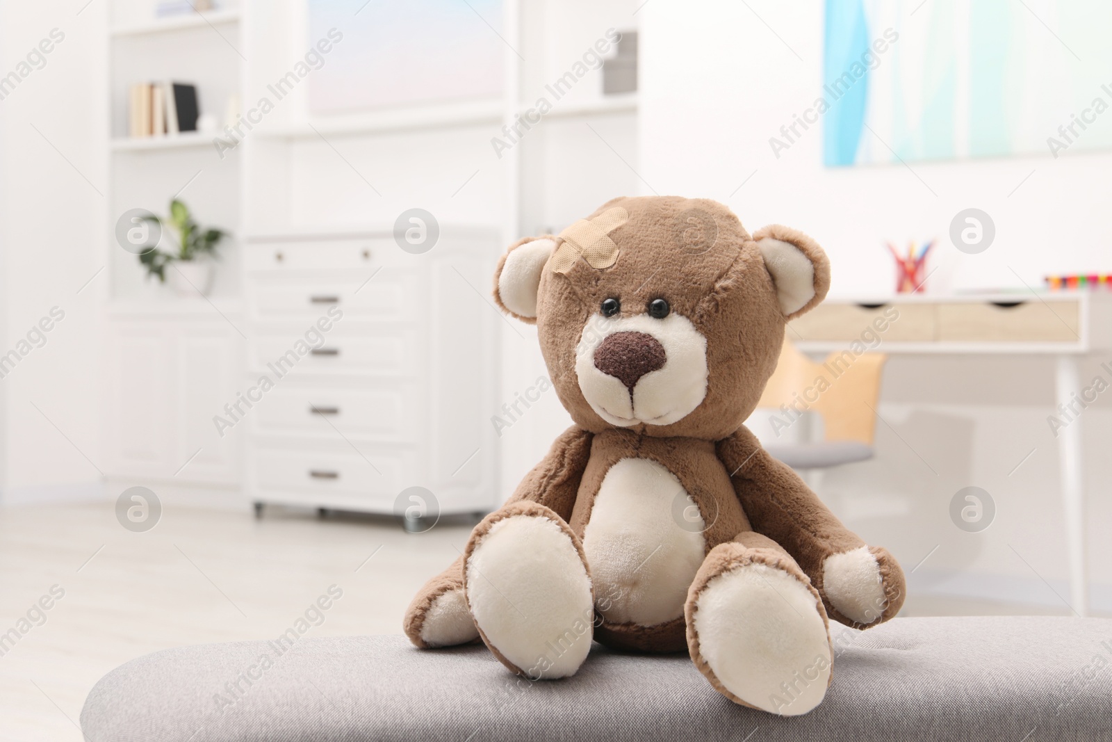 Photo of Toy cute bear with sticking plaster indoors, space for text