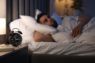 Frustrated man suffering from insomnia on bed, selective focus