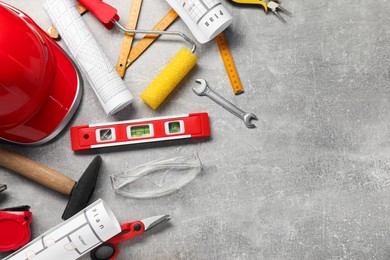 Flat lay composition with building level and other construction tools on grey table, space for text