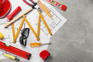 Flat lay composition with building level and other construction tools on grey table, space for text