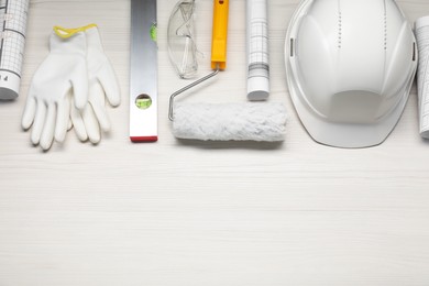 Flat lay composition with building level and other construction tools on white wooden table, space for text