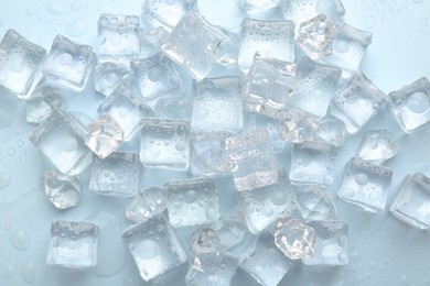 Photo of Crystal clear ice cubes on light blue background, flat lay