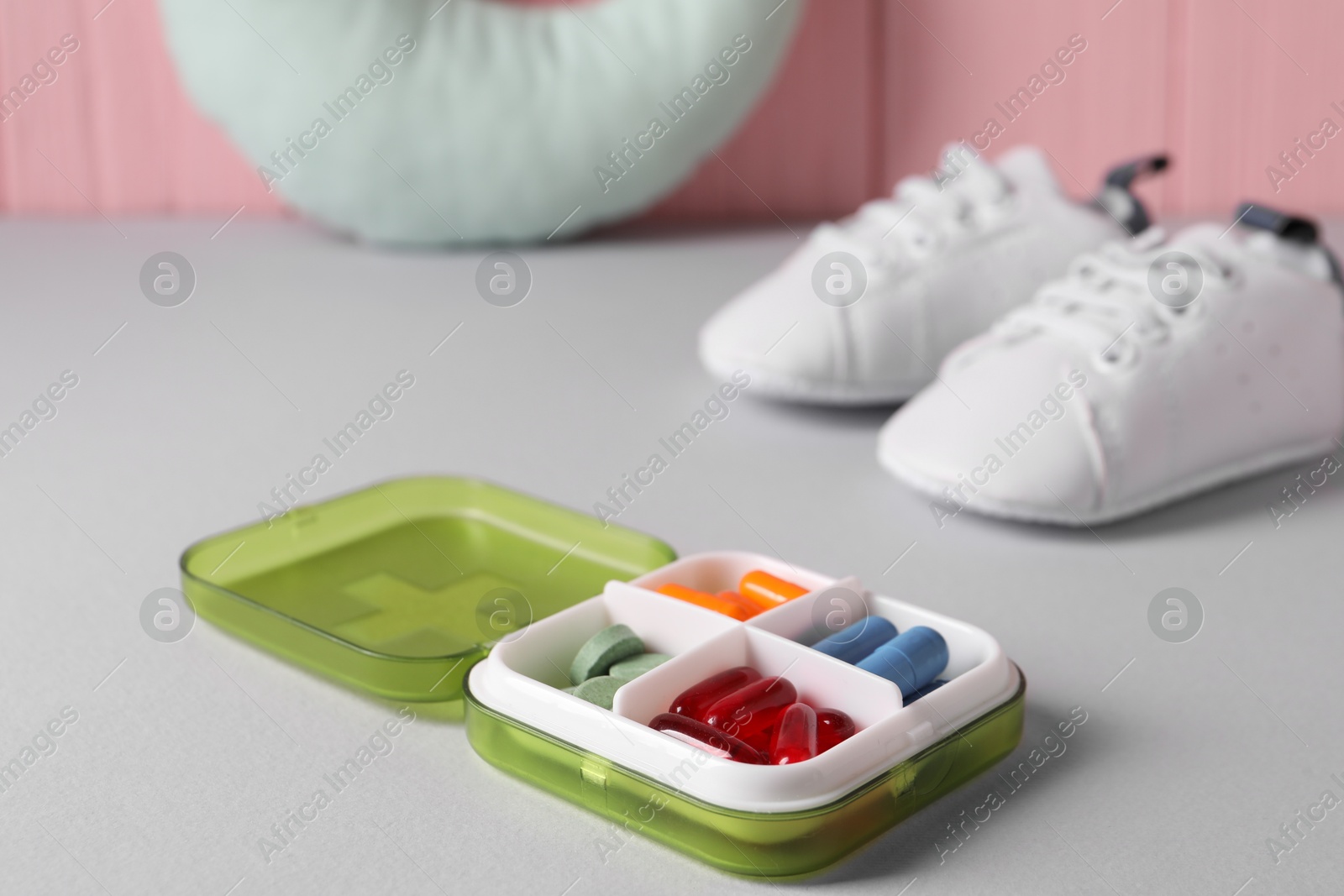 Photo of Different pills in container on grey table, closeup