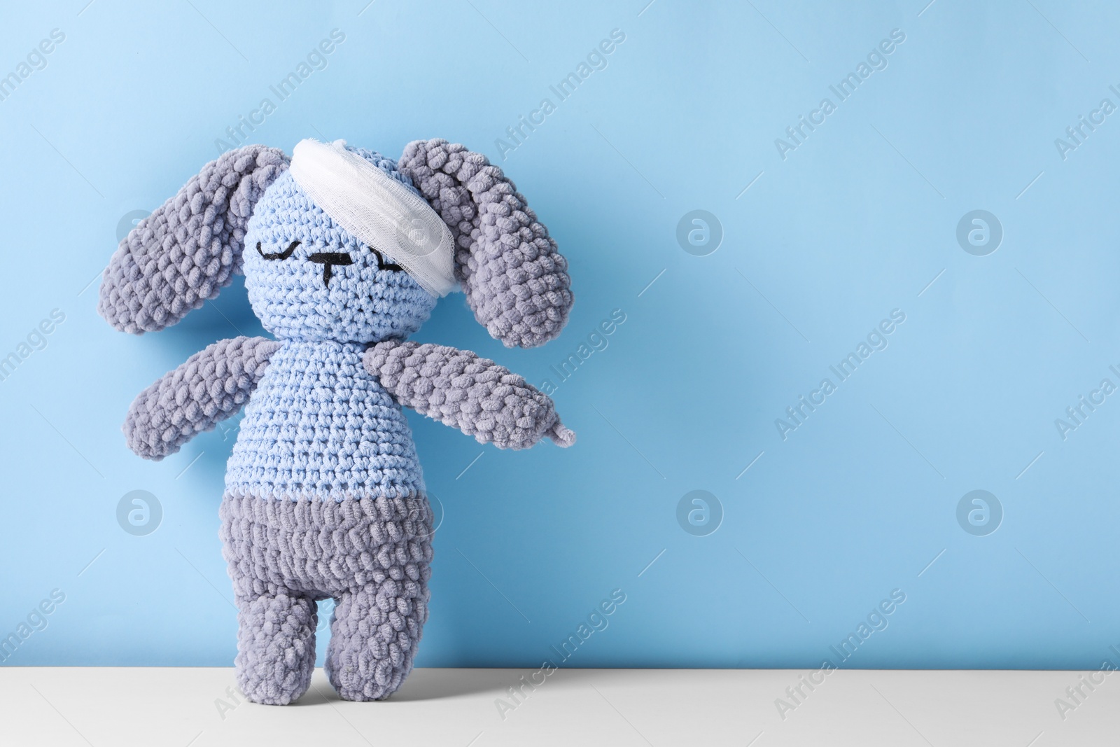 Photo of Toy bunny with bandage on color background, space for text