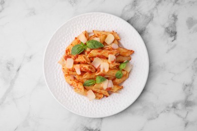 Photo of Tasty pasta with tomato sauce, cheese and basil on white marble table, top view