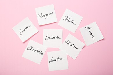 Photo of Paper stickers with different names on pink background, flat lay. Choosing baby's name