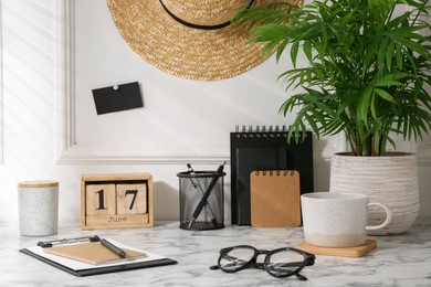 Photo of Stylish office workplace. Decor elements, glasses, cup and stationery on marble table near white wall