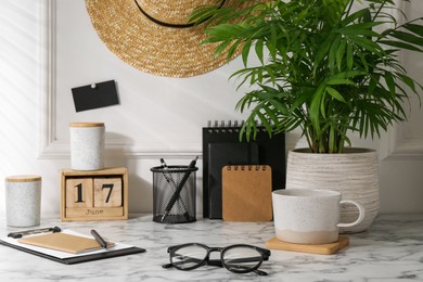 Stylish office workplace. Decor elements, glasses, cup and stationery on marble table near white wall