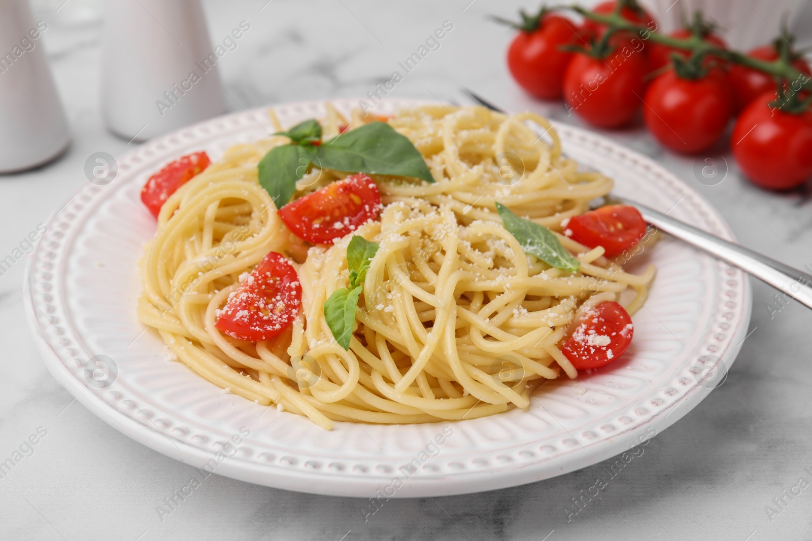 Photo of Tasty pasta with tomato, cheese and fork on white marble table, closeup