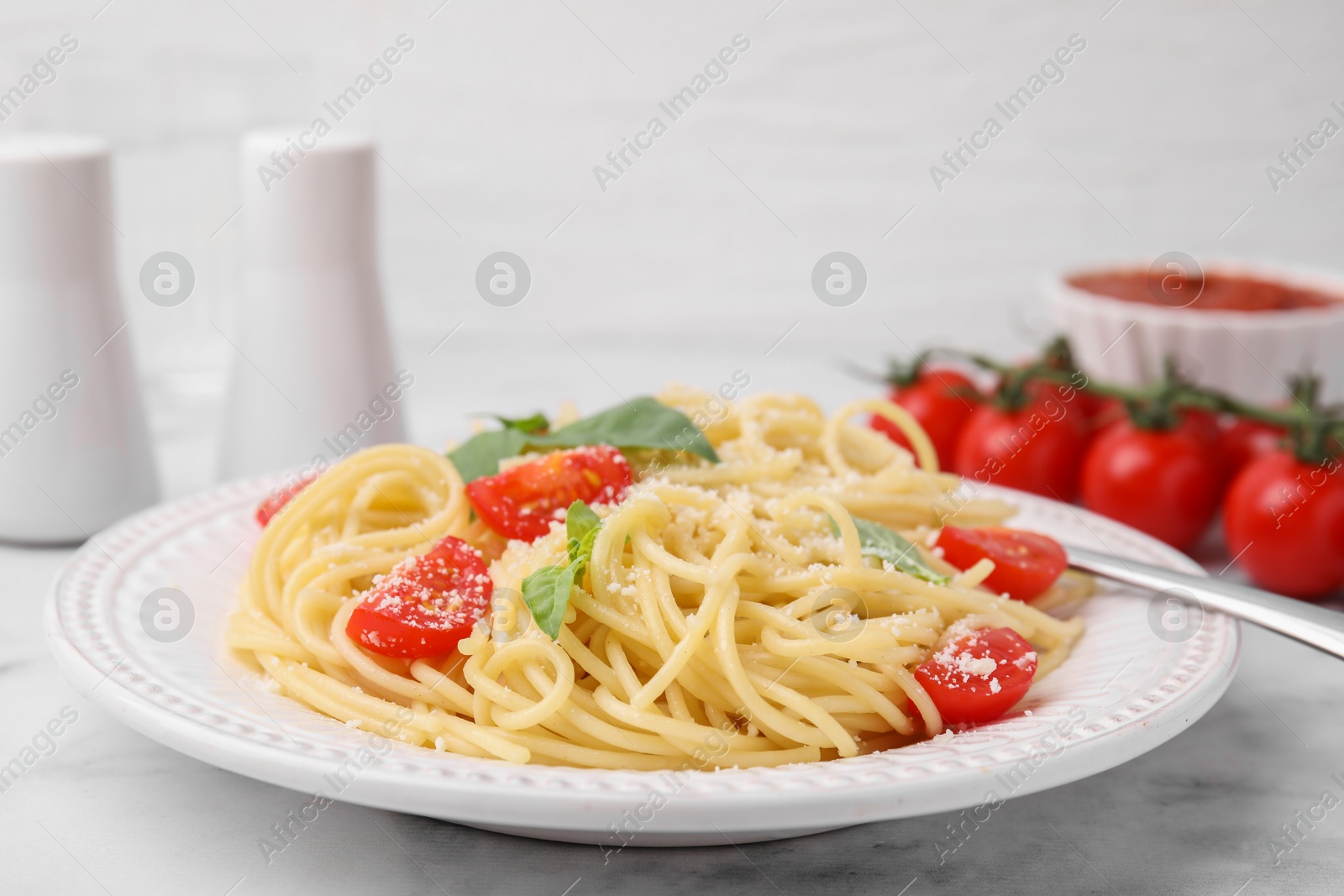 Photo of Tasty pasta with tomato, cheese and fork on white marble table, closeup