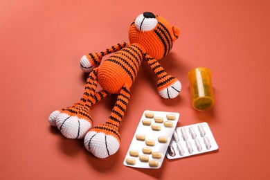 Photo of Toy tiger and pills on orange background