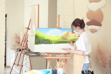 Photo of Woman drawing landscape with brush in studio