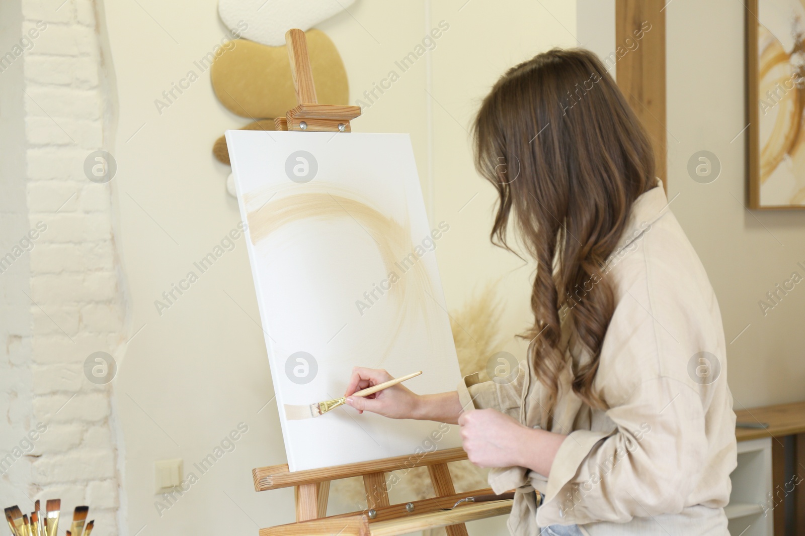 Photo of Woman drawing on easel with canvas in studio