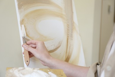 Photo of Woman with palette knife drawing picture in studio, closeup