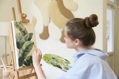Photo of Woman with brush painting tropical leaves in studio