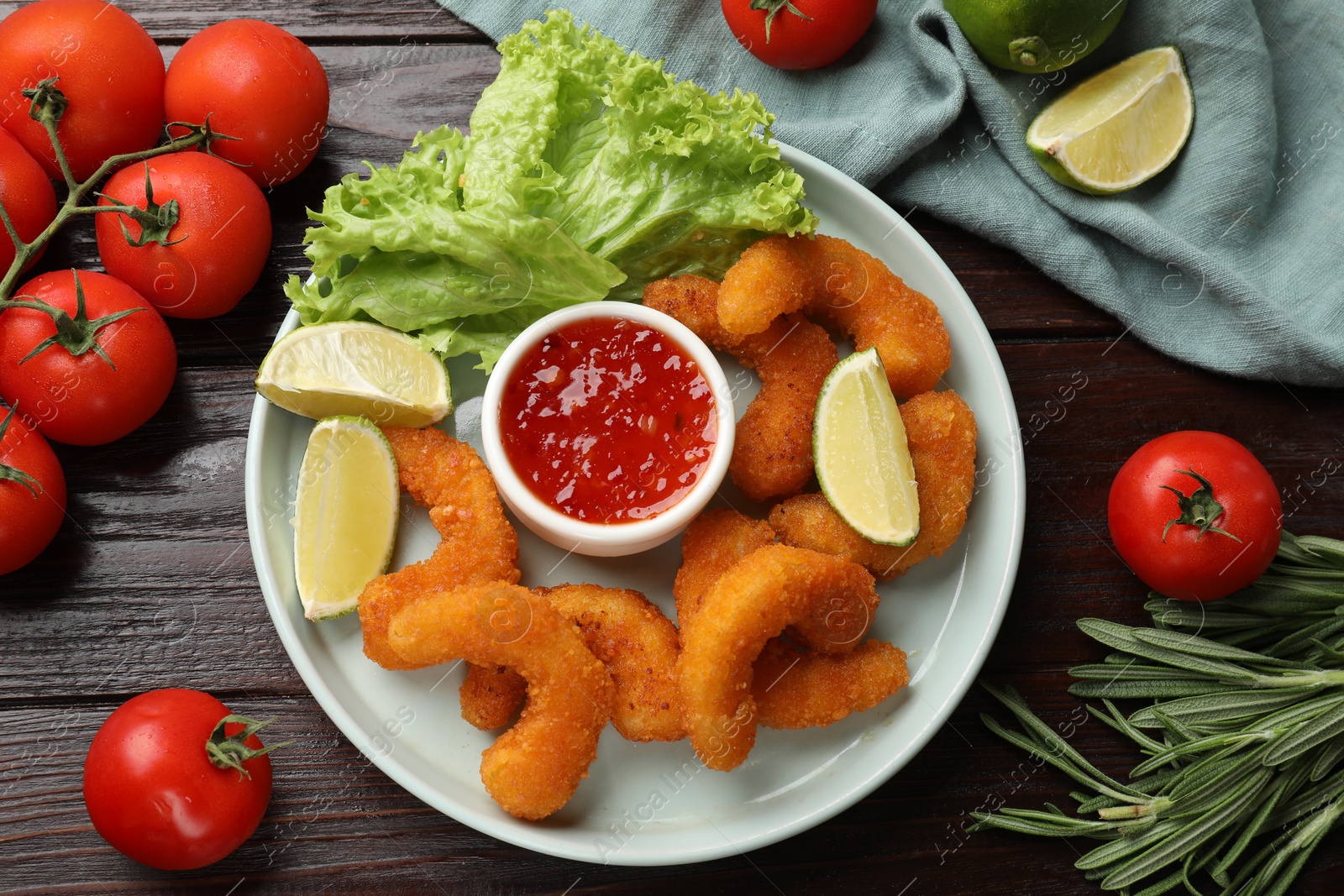 Photo of Delicious breaded fried shrimps served with lime and sauce on wooden table, top view