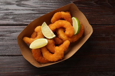 Delicious breaded fried shrimps and lime on wooden table, top view