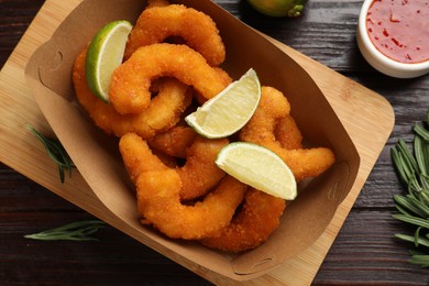 Delicious breaded fried shrimps served with lime on wooden table, top view