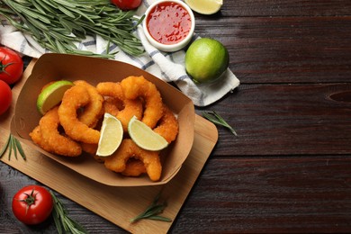 Delicious breaded fried shrimps served with lime and sauce on wooden table, top view. Space for text