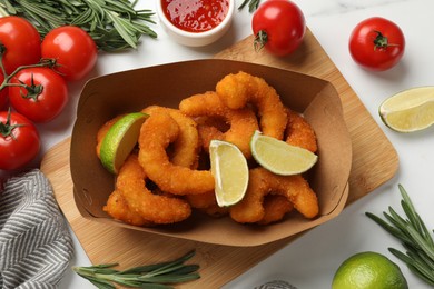 Delicious breaded fried shrimps served with lime on white table, top view