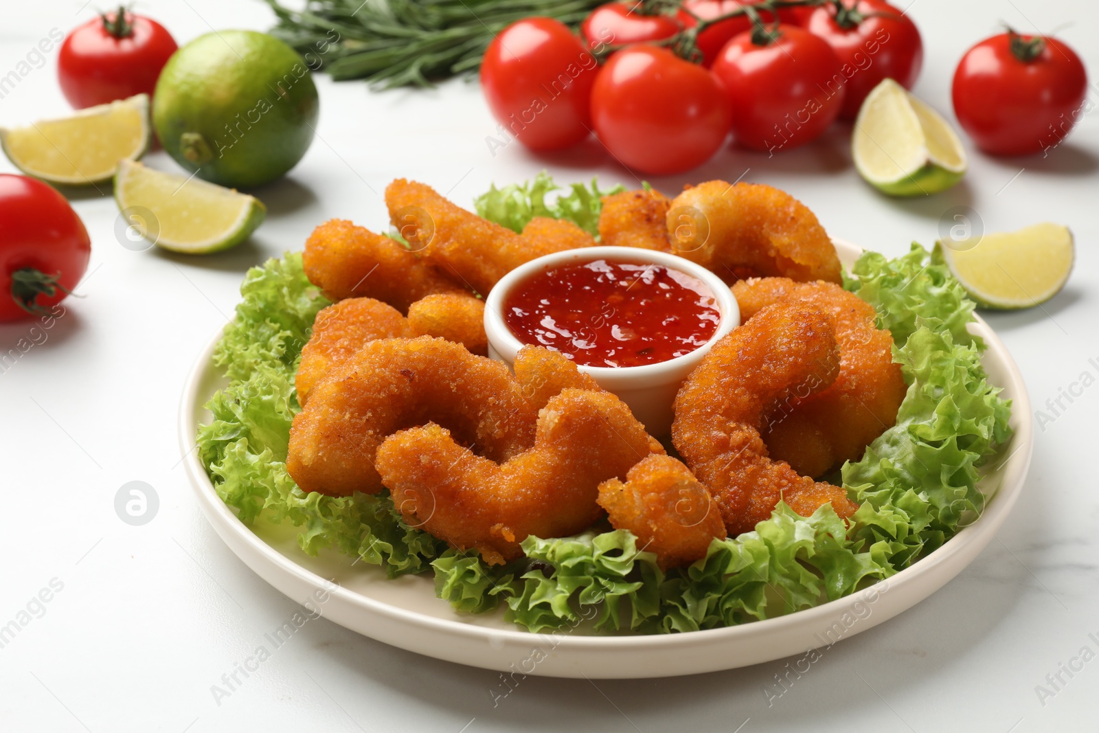 Photo of Delicious breaded fried shrimps served with sauce on white marble table