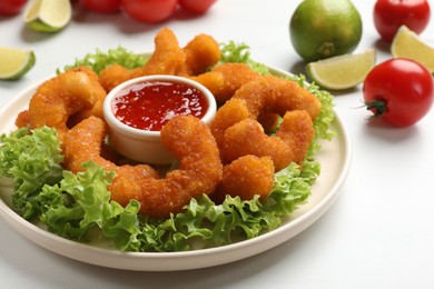 Photo of Delicious breaded fried shrimps served with sauce on white table