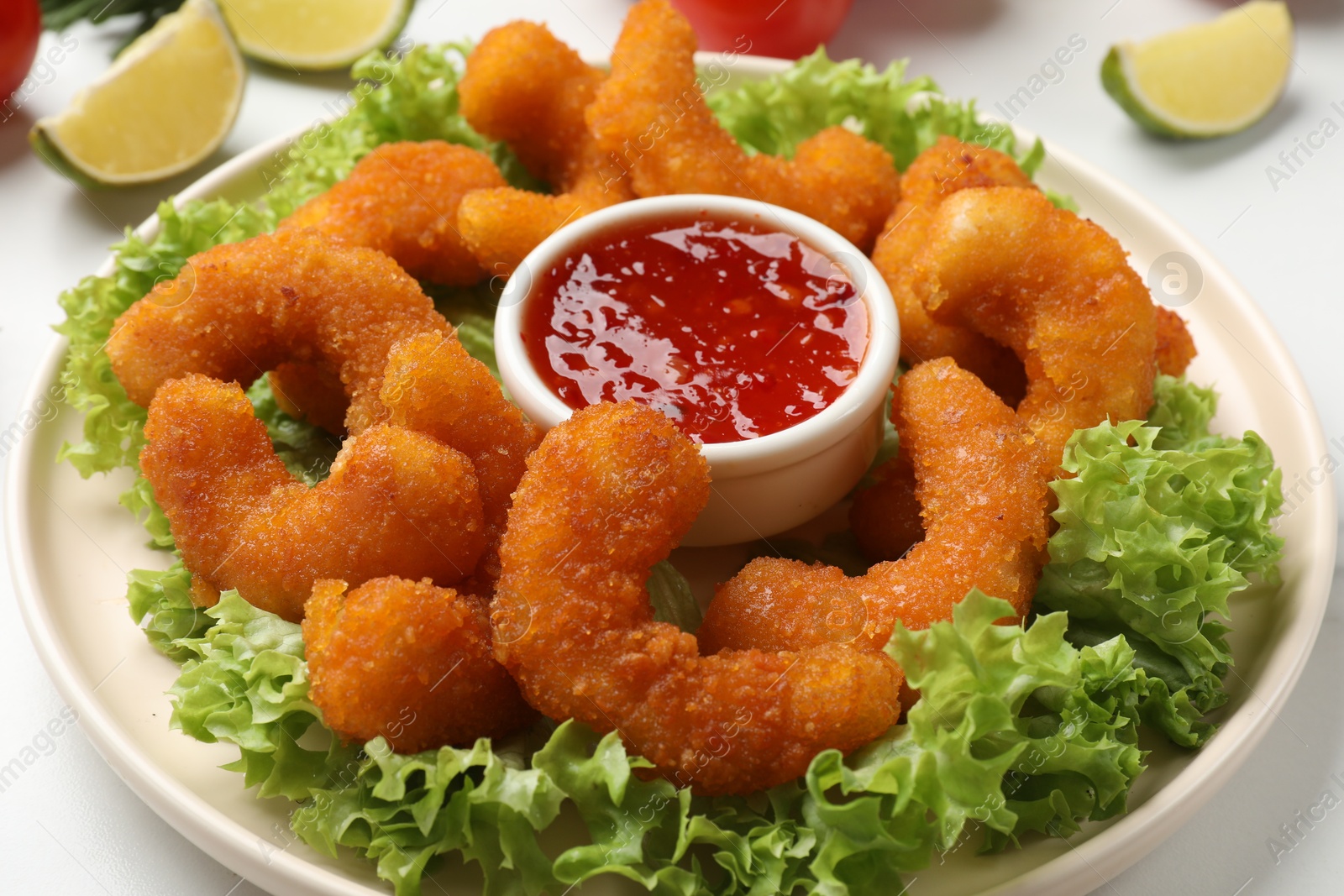 Photo of Delicious breaded fried shrimps, sauce and lettuce on table, closeup