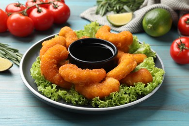 Photo of Delicious breaded fried shrimps served with sauce on light blue wooden table