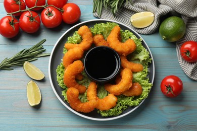 Photo of Delicious breaded fried shrimps served with sauce on light blue wooden table, top view