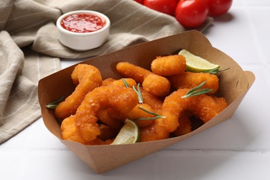 Photo of Delicious breaded fried shrimps, lime, rosemary and sauce on white table