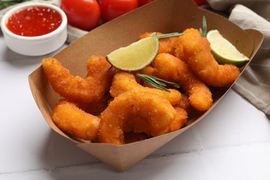 Photo of Delicious breaded fried shrimps, lime, rosemary and sauce on white table, closeup