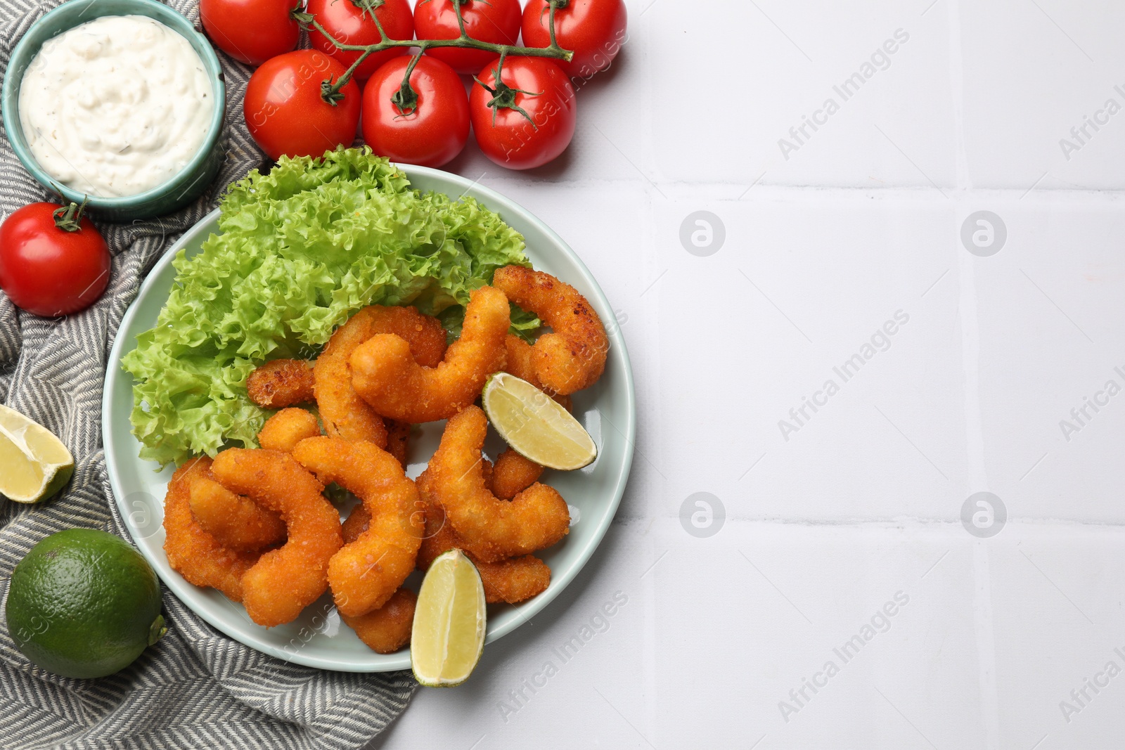 Photo of Delicious breaded fried shrimps served on white tiled table, top view. Space for text