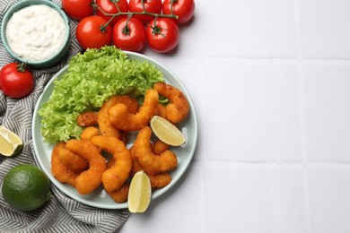 Photo of Delicious breaded fried shrimps served on white tiled table, top view. Space for text