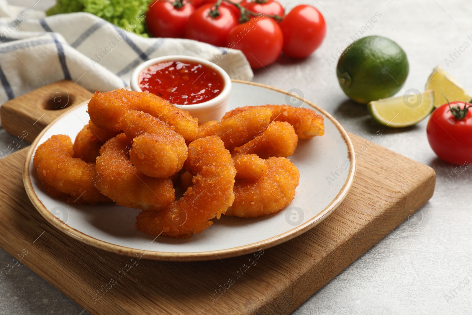 Photo of Delicious breaded fried shrimps served with sauce on light grey table