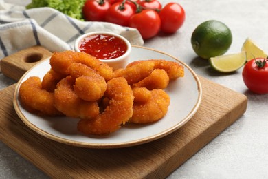 Delicious breaded fried shrimps served with sauce on light grey table