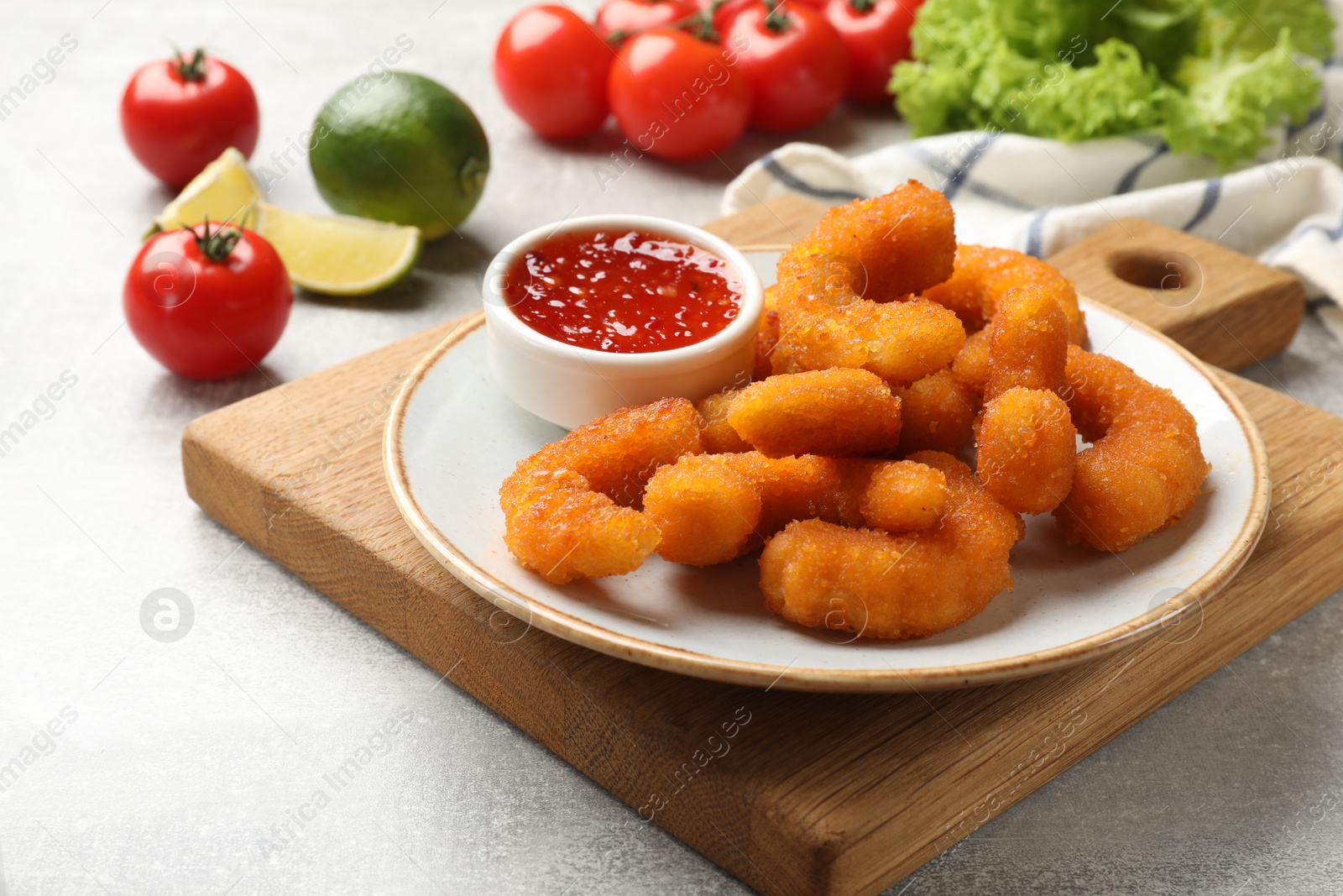 Photo of Delicious breaded fried shrimps served with sauce on light grey table