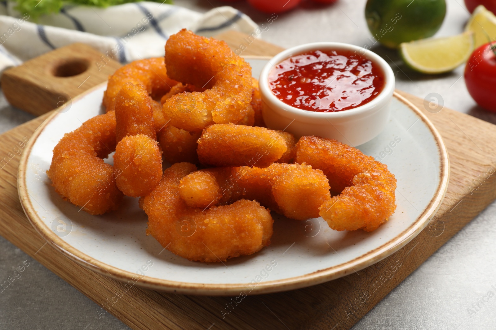 Photo of Delicious breaded fried shrimps and sauce on light grey table, closeup