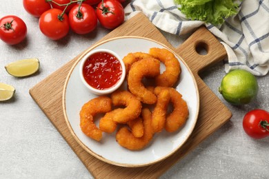 Delicious breaded fried shrimps served with sauce on light grey table, top view