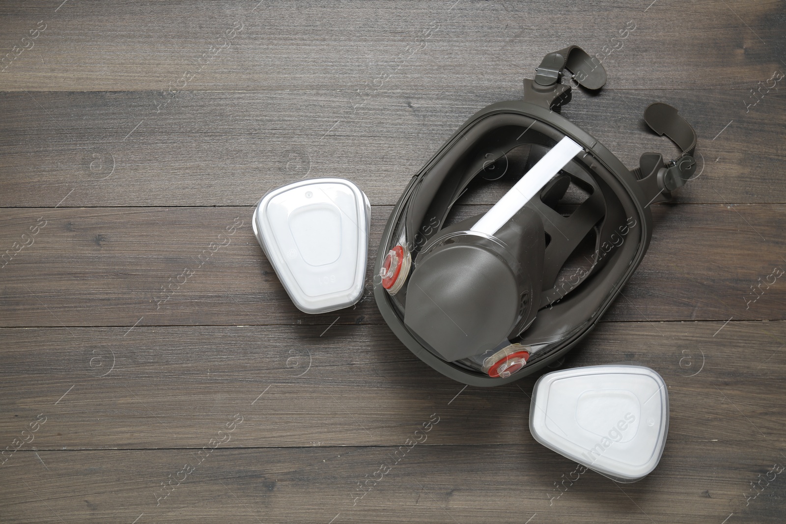 Photo of Respirator mask and filters on wooden table, top view. Space for text