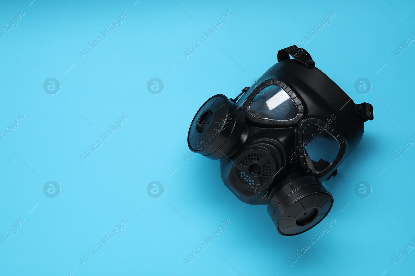 Photo of One gas mask on light blue background, top view. Space for text