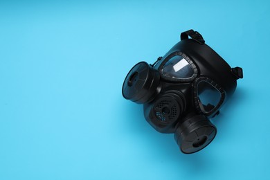 Photo of One gas mask on light blue background, top view. Space for text