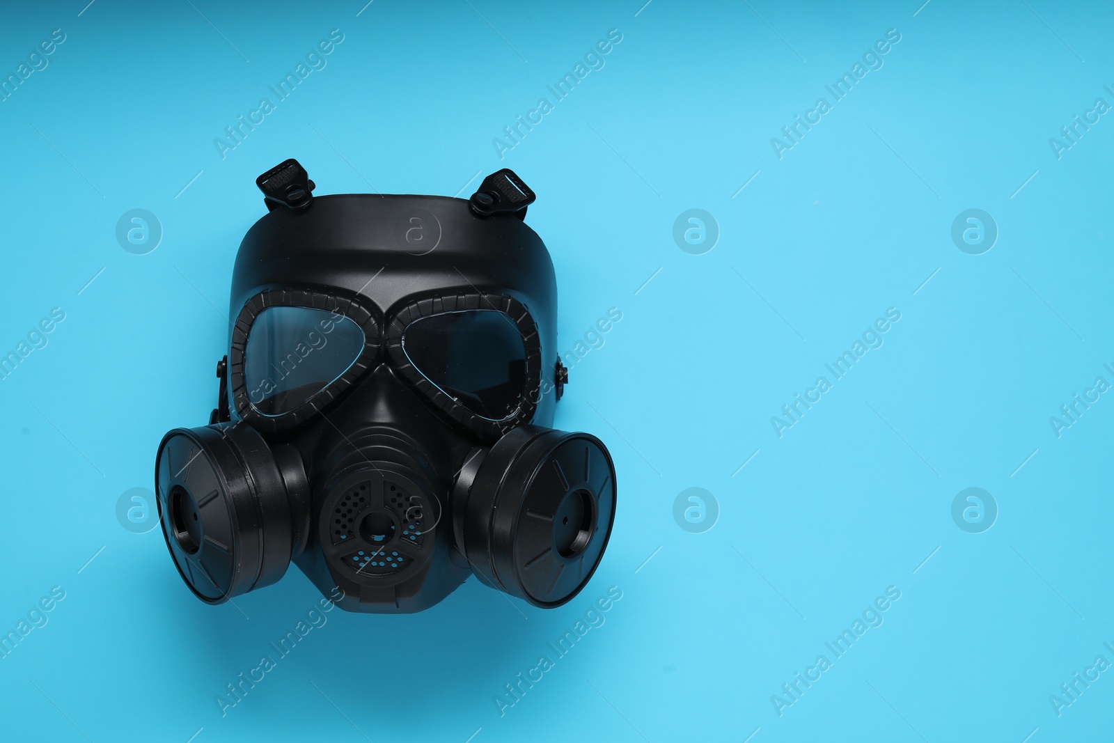 Photo of One gas mask on light blue background, top view. Space for text