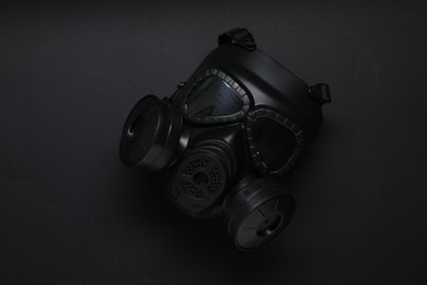 One gas mask on black background, top view. Safety equipment