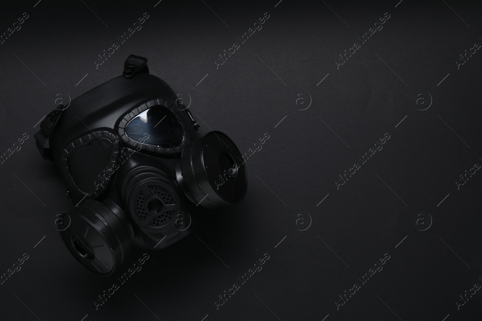 Photo of One gas mask on black background, top view and space for text. Safety equipment